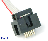 Shrouded 2×3-pin box header with a ribbon cable and IDC connector plugged into it.